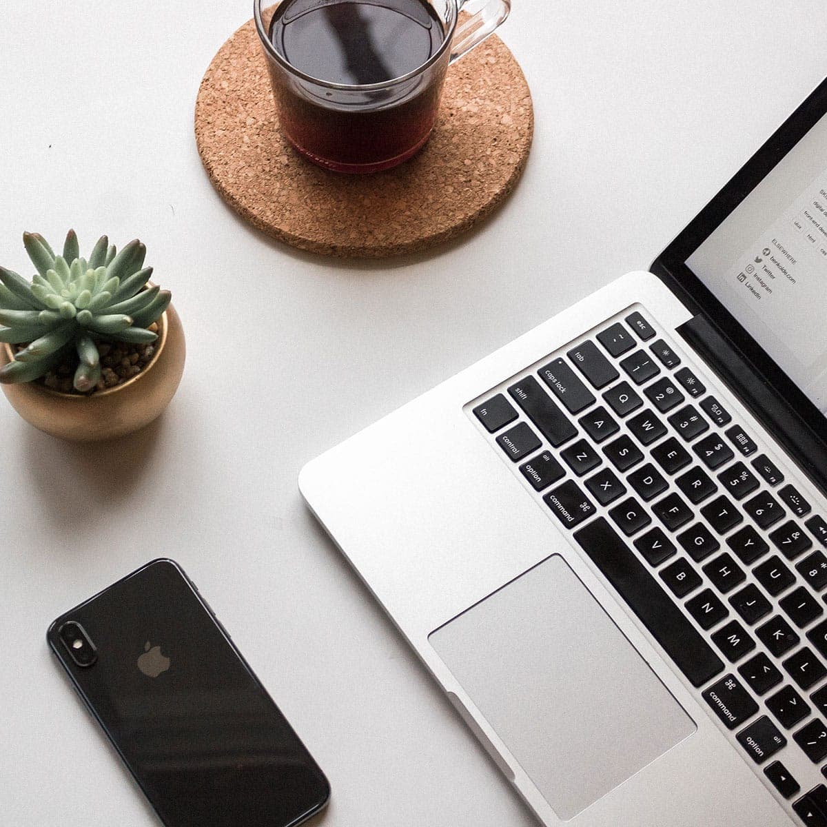 Desk with laptop, coffee and a little plant